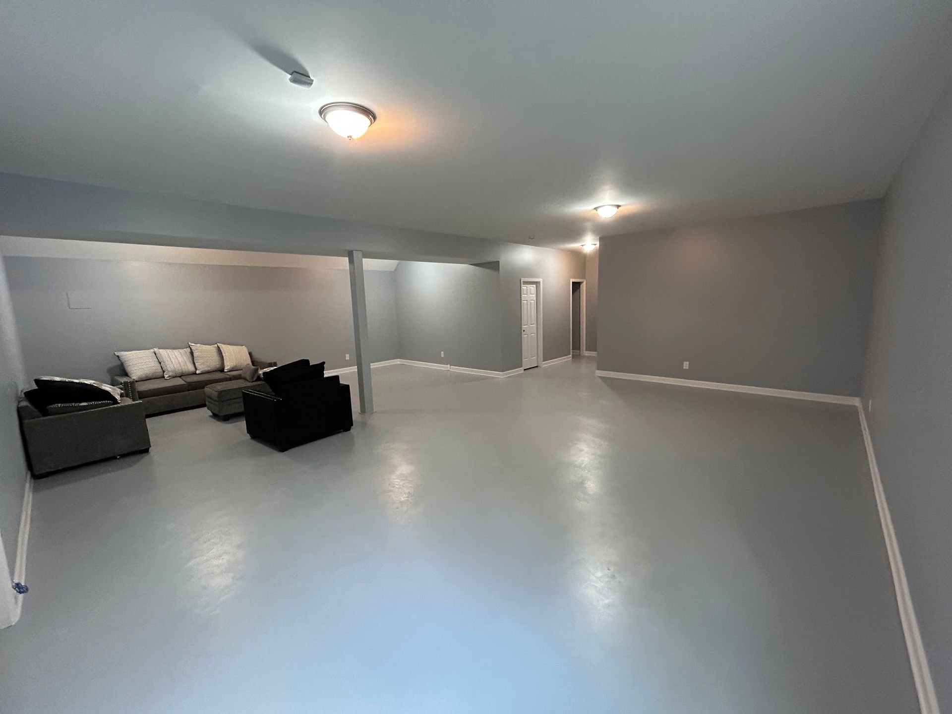 A large empty room with a couch and chairs in it.