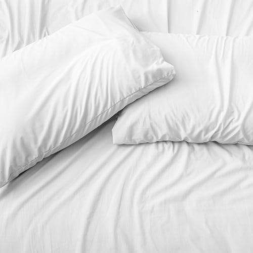 Two white bed pillows rest on a white, wrinkled bed sheet.