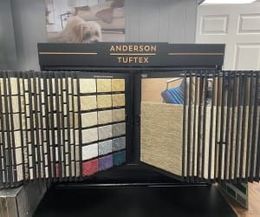 An Anderson Tuftex floor sample display rack featuring rows of various carpet color swatches and textures.