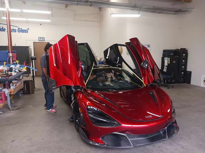 A man is working on a black car in a garage