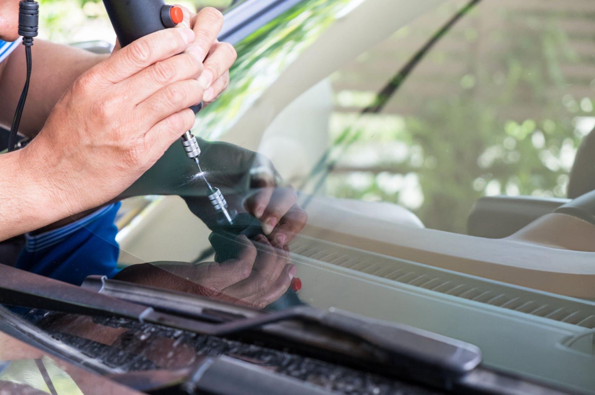 A person using a screwdriver to fix a windshield A person using a screwdriver to fix a windshield