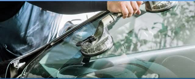 A man is fixing a windshield on a car.