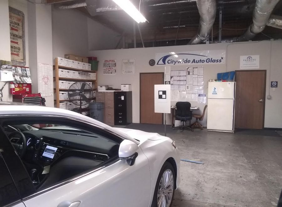 A white car is parked in a garage with a sign that says city auto glass