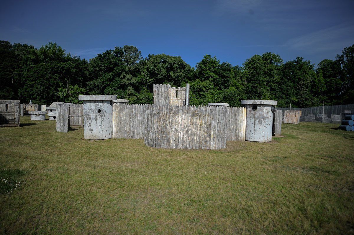 A large concrete structure in the middle of a grassy field with trees in the background.