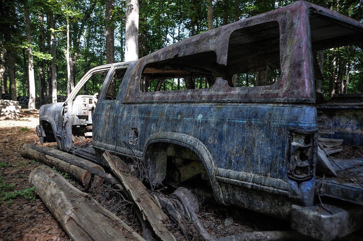 A blue truck is sitting in the middle of a forest.