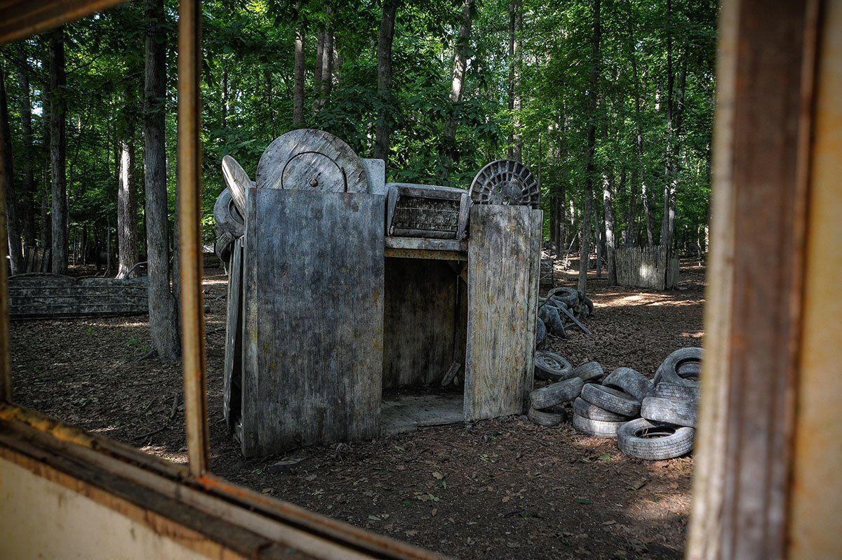 A building in the middle of a forest is visible through a window.
