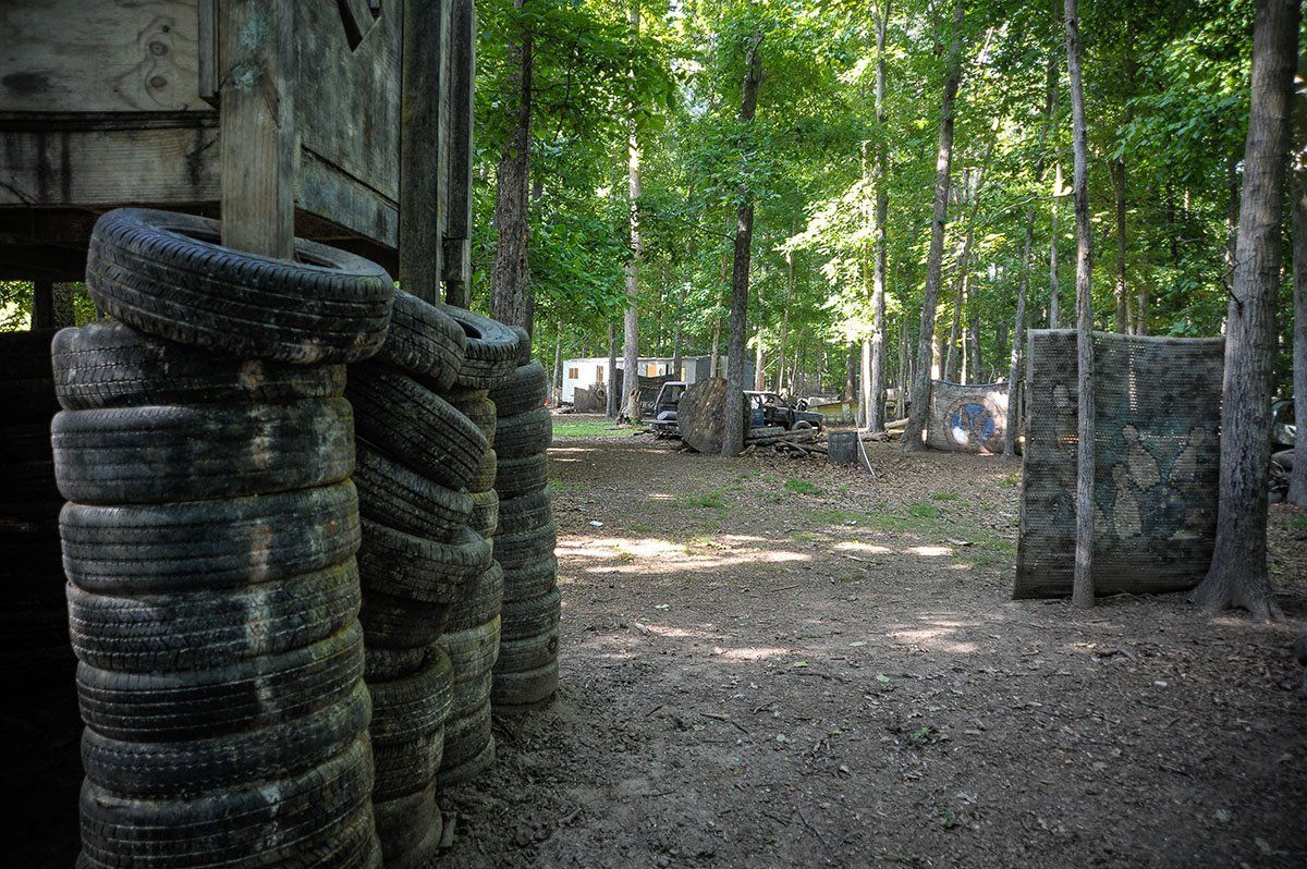 A bunch of tires are stacked on top of each other in the middle of a forest.