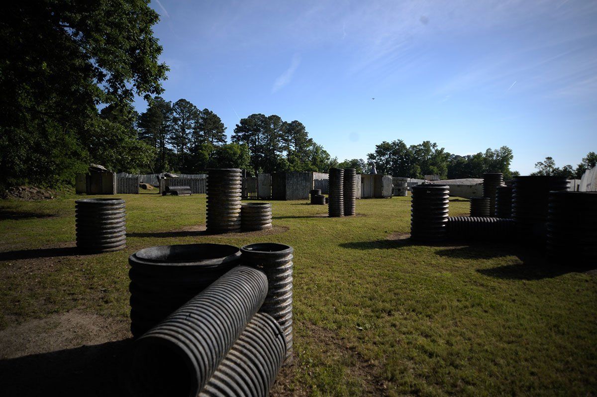 A paintball field with a lot of barrels and trees in the background