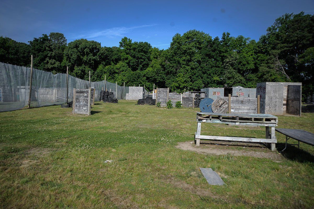 A paintball field with a fence and a bench in the middle of it.