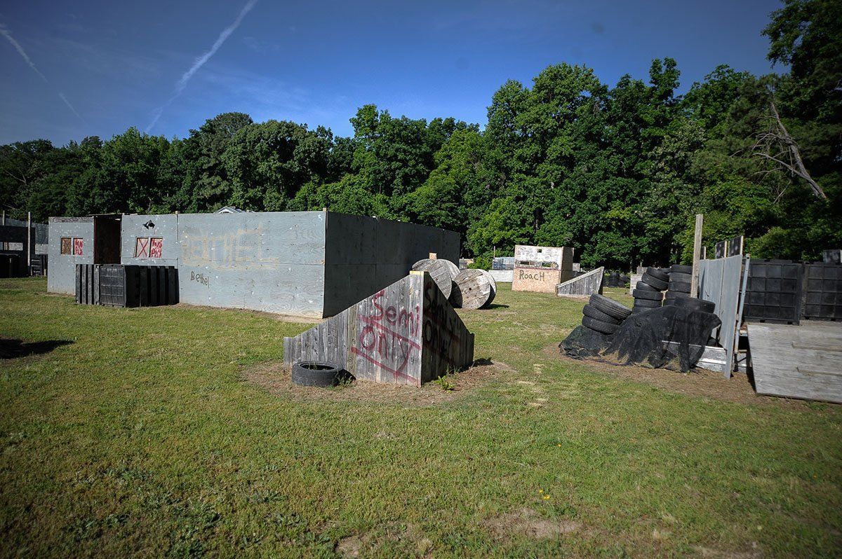 A paintball field with a lot of buildings and trees in the background.