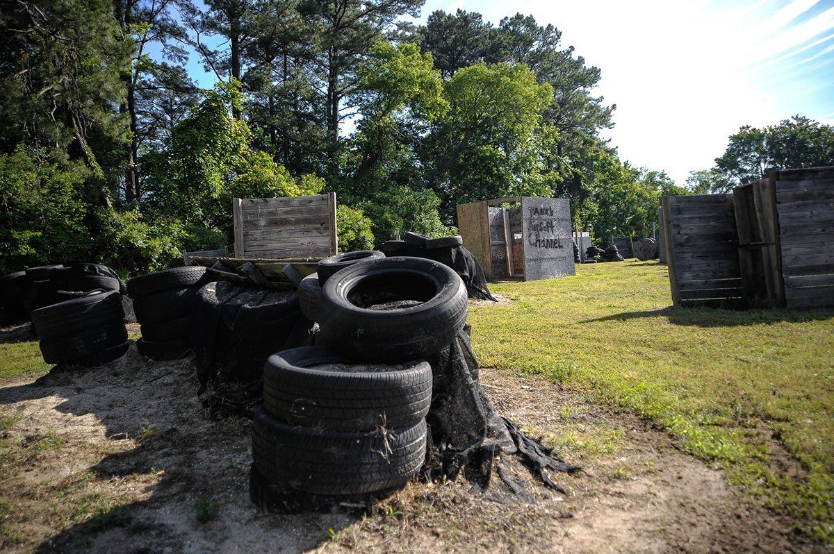 A bunch of tires are stacked on top of each other in a field.
