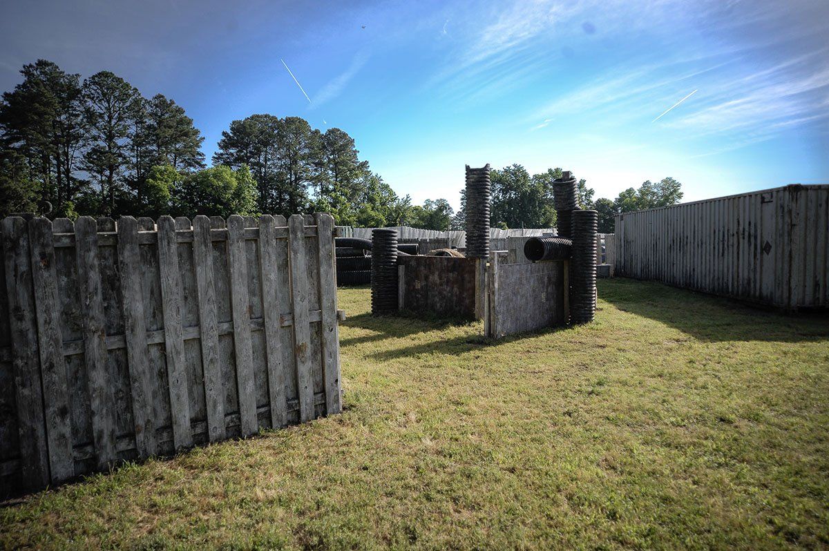 A wooden fence is in the middle of a grassy field.