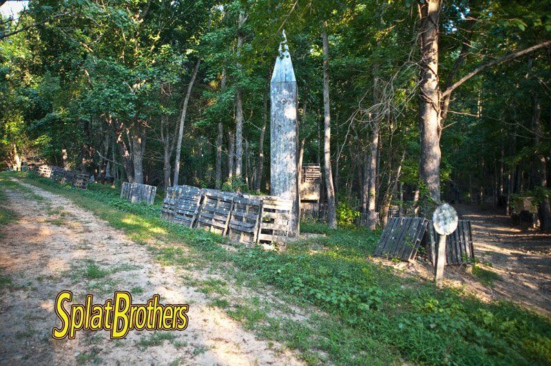 A dirt road in the middle of a forest with a sign that says splat brothers.