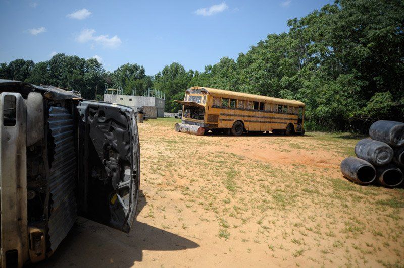 A yellow school bus is parked in a dirt field.