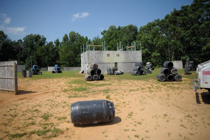A paintball field with a bunch of barrels in the middle of it.
