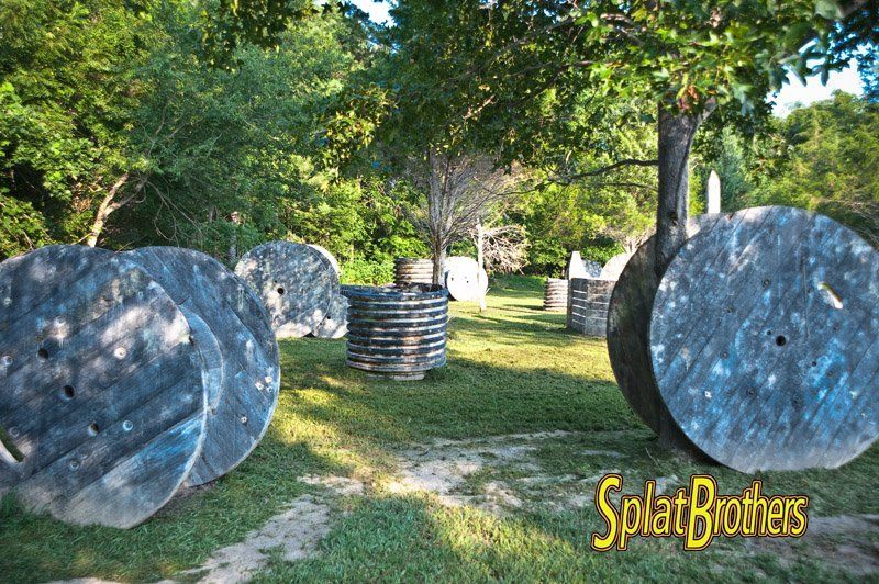 A paintball field with a bunch of spools in the grass.