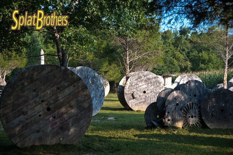 A bunch of wooden spools are sitting on top of each other in a field.