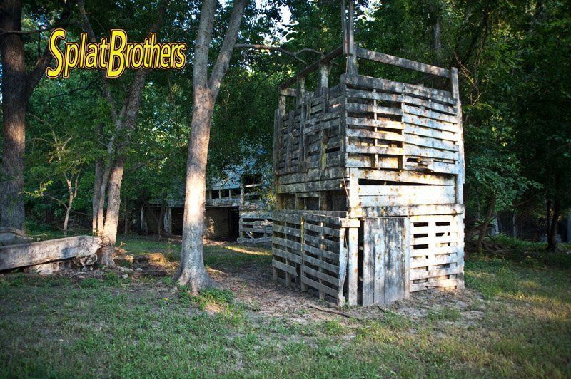 A wooden structure in the middle of a field with a sign that says splat brothers