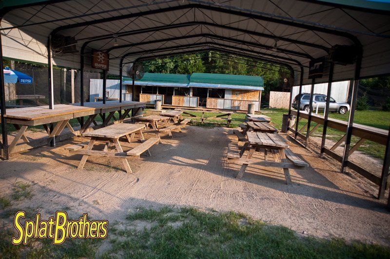 A group of picnic tables under a tent with the words splat brothers written on the bottom