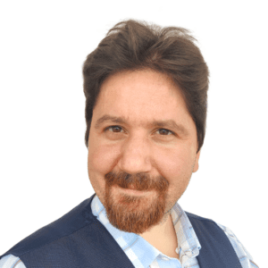 A man with a beard and a blue vest is smiling for the camera.