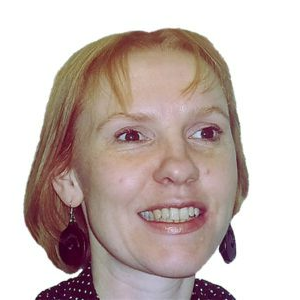 A woman with red hair is smiling and wearing earrings