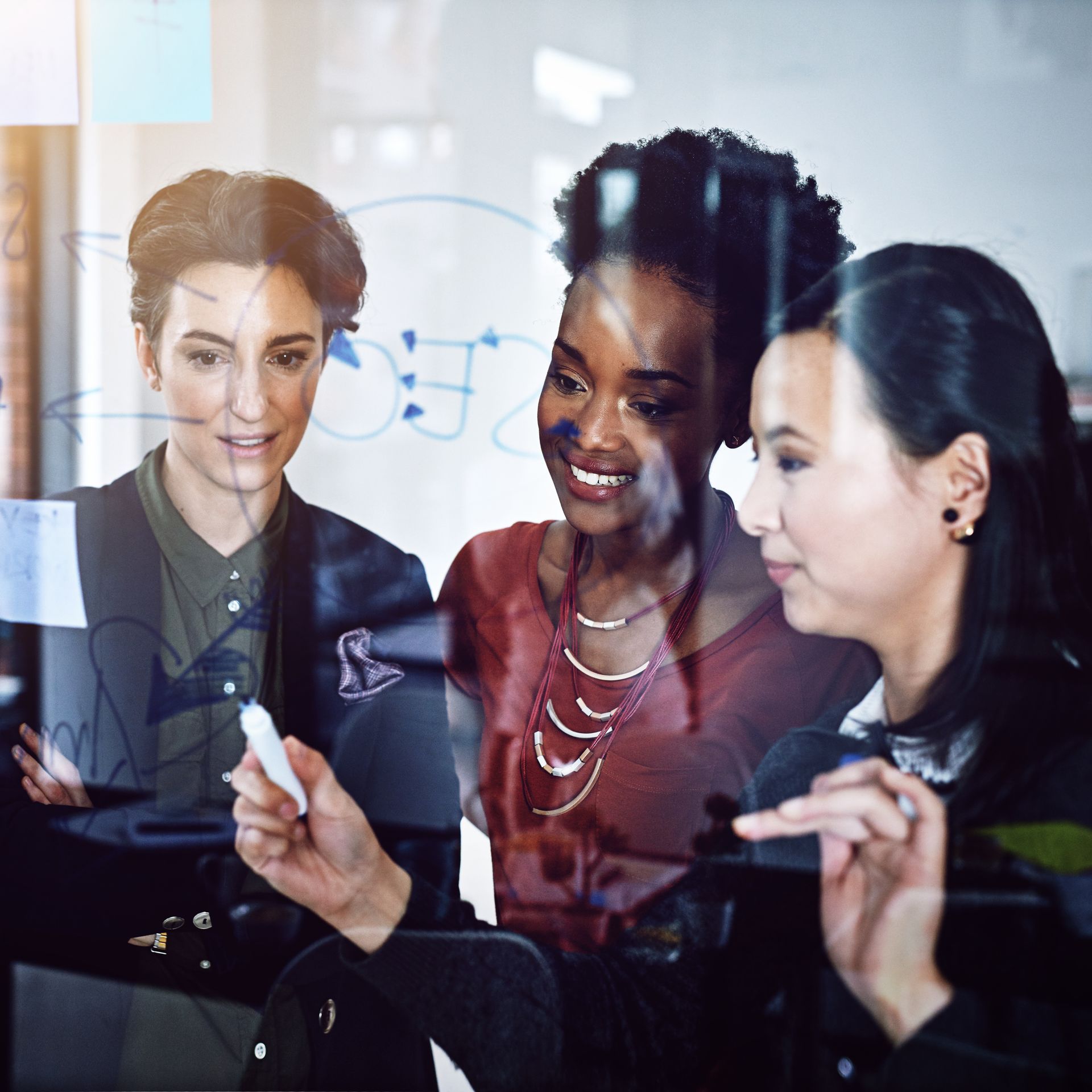 Three women are looking at a computer screen together.