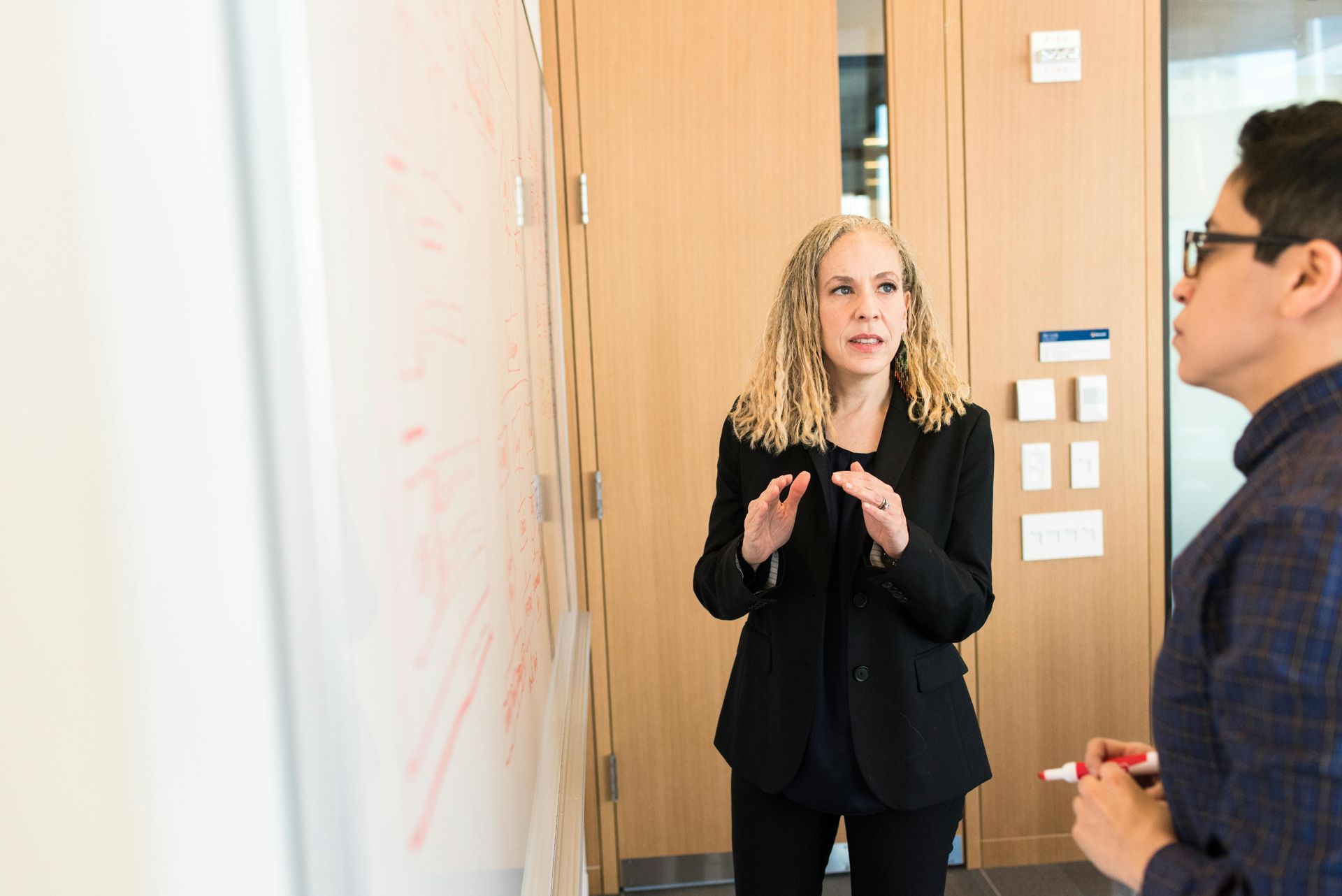 A man and a woman are standing in front of a whiteboard.