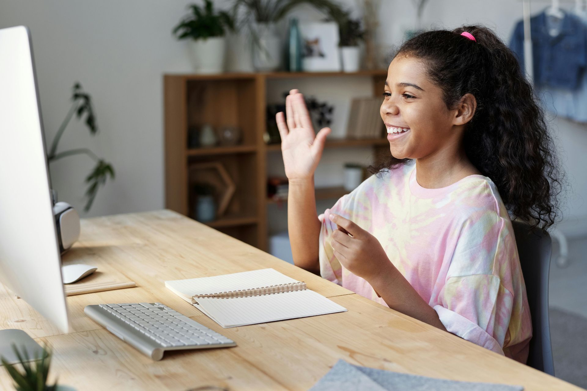 A young girl is sitting at a desk in front of a computer.
