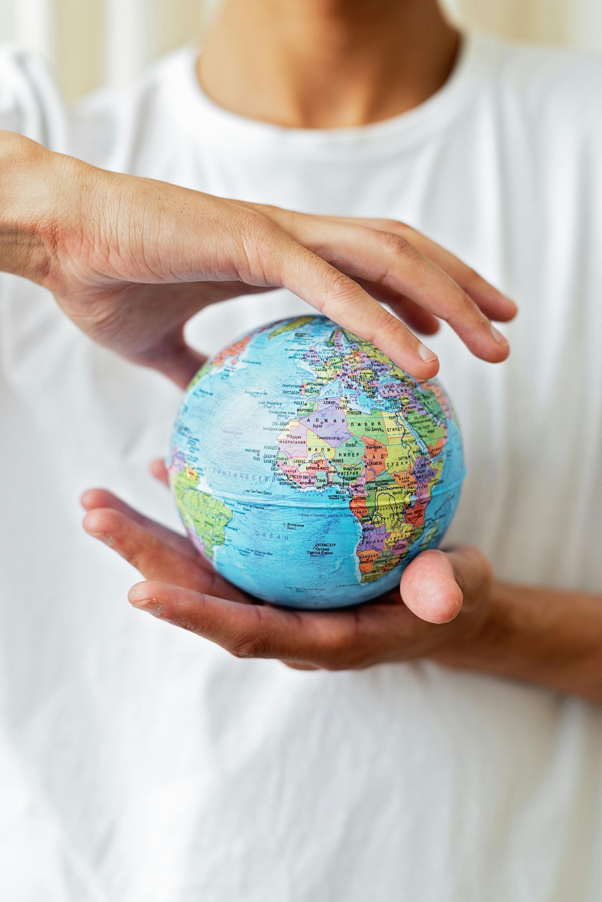 A person is holding a small globe in their hands.