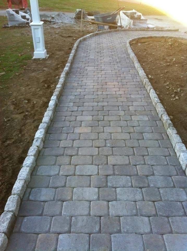 Brick path with light borders leading into a garden setting.
