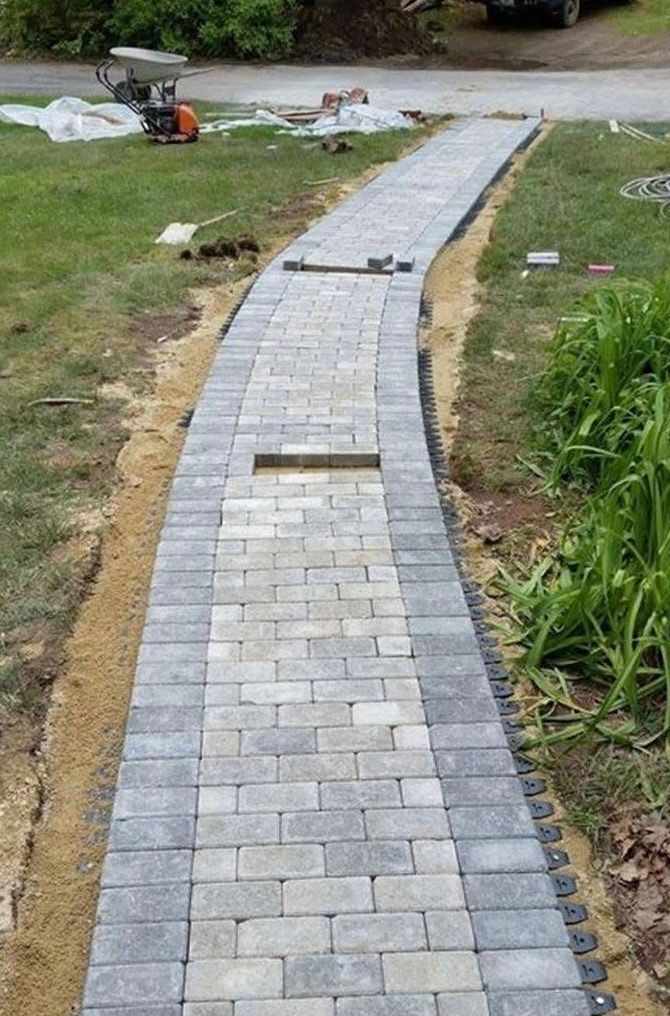 Brick pathway under construction with a light gray center and dark gray borders in a yard.