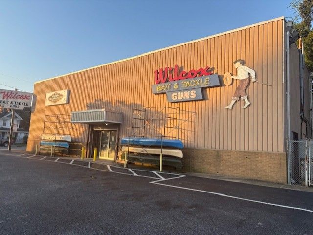 Wilcox Bait & Tackle shop sign with figure of fisherman, and guns.