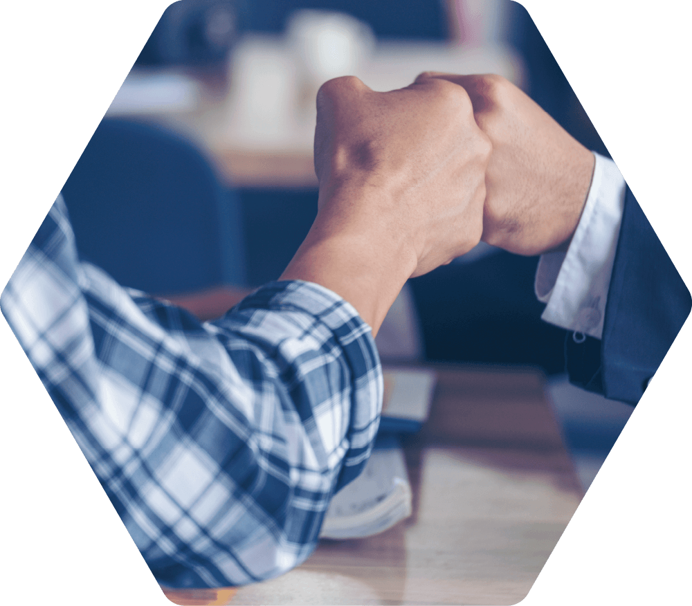 Two people bumping fists in a gesture of agreement; one wearing a plaid shirt, the other a suit.