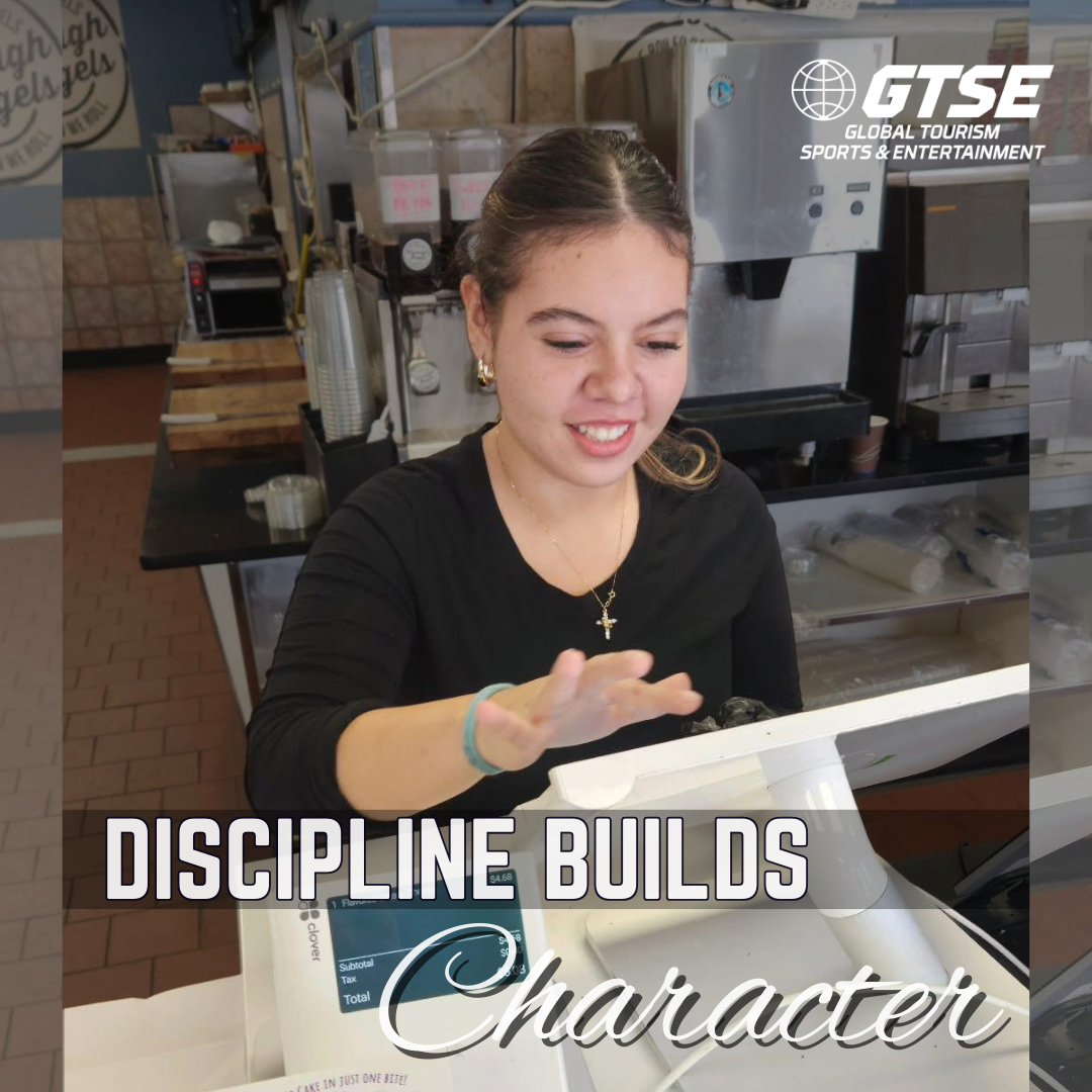 Woman smiles at a cash register, gesturing with hand. 