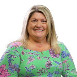 Lola Moore smiling in a green floral blouse against a white background
