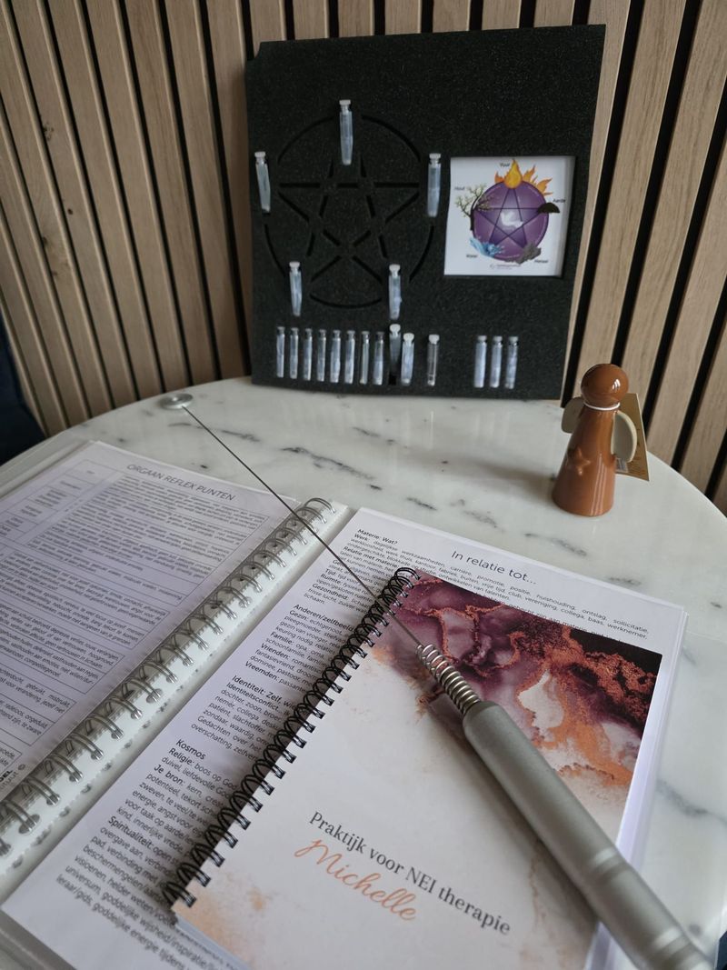 Een tafel met een boek, staven en bakjes. Op de achtergrond een gedecoreerd paneel.