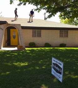Two men are standing on the roof of a house Two men are standing on the roof of a house