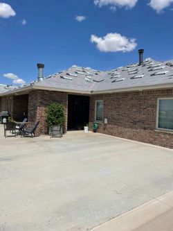 A brick house with a gray roof and a driveway A brick house with a gray roof and a driveway