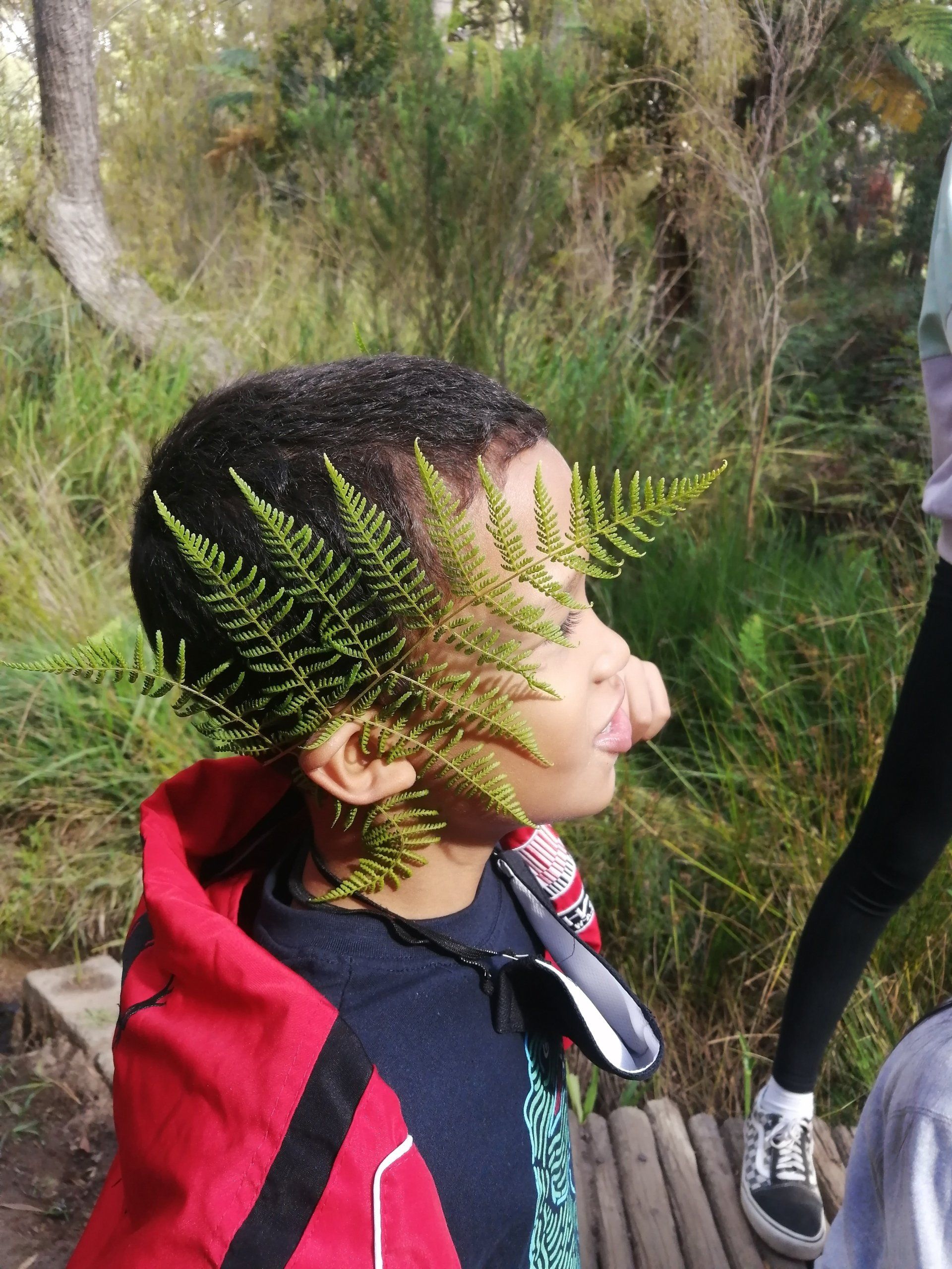 a young boy with a fern leaf on his head