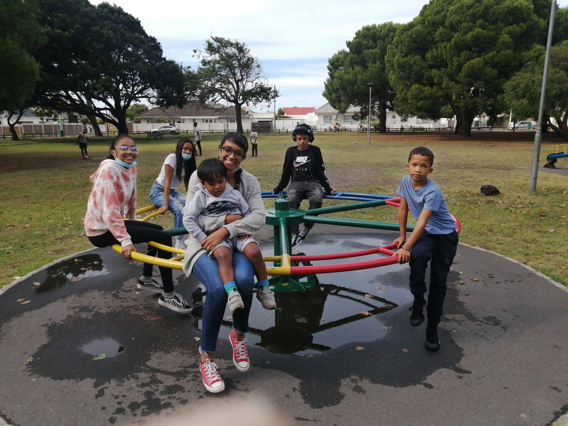 a group of people are playing on a merry go round in a park .