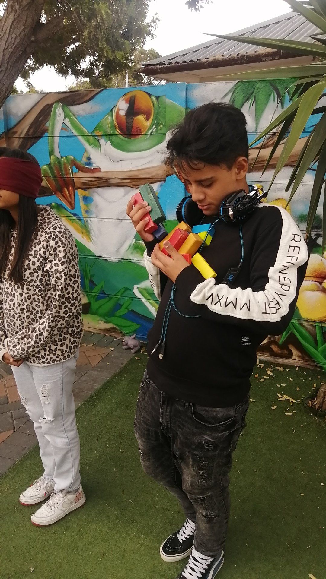 a boy and a girl are standing next to each other in front of a mural .