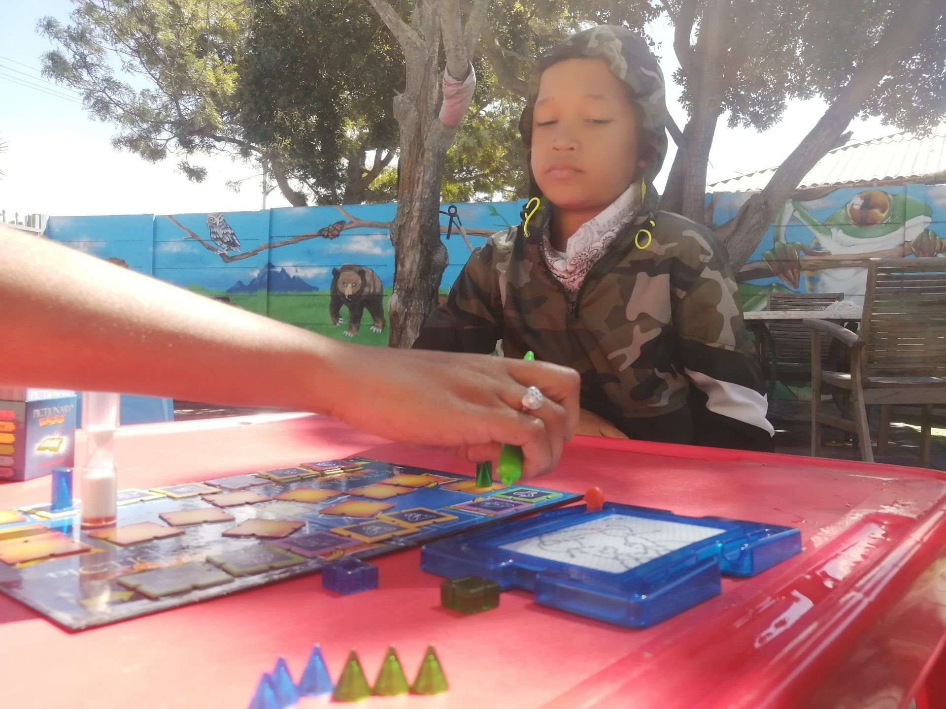 a boy in a camouflage jacket is playing a board game