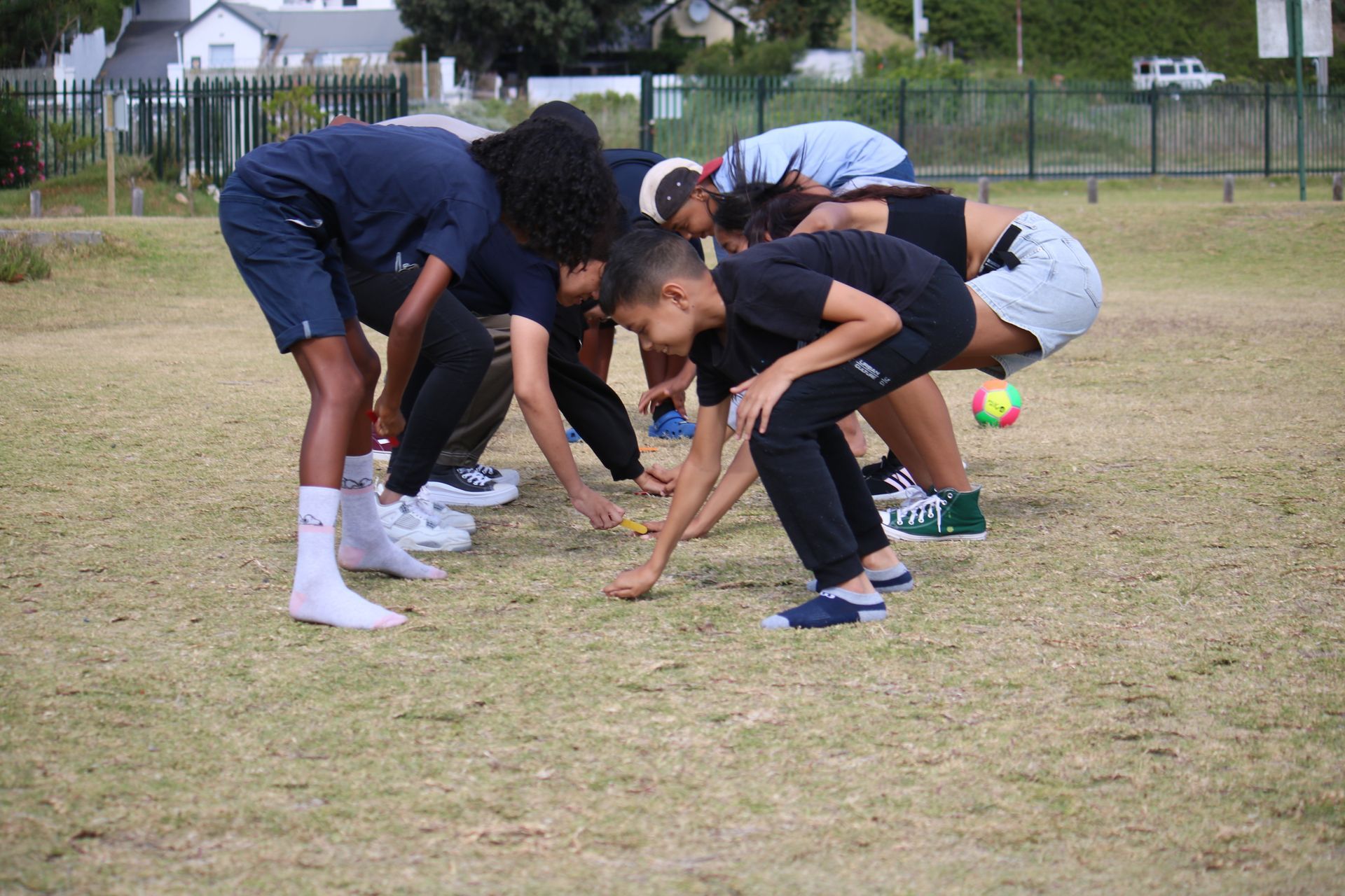 a group of children are squatting on the grass in a field .