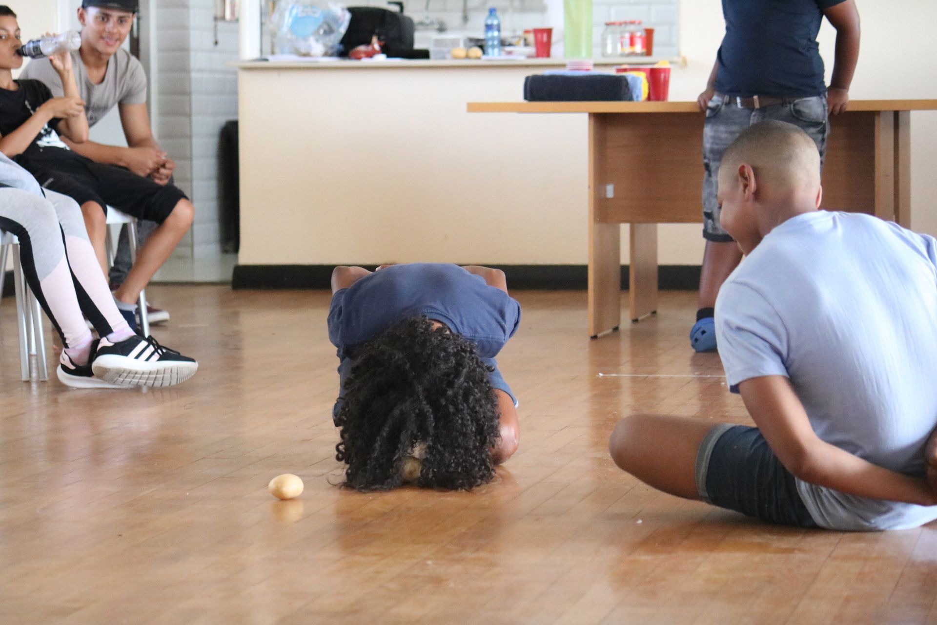 a group of children are playing a game with a ball on the floor .
