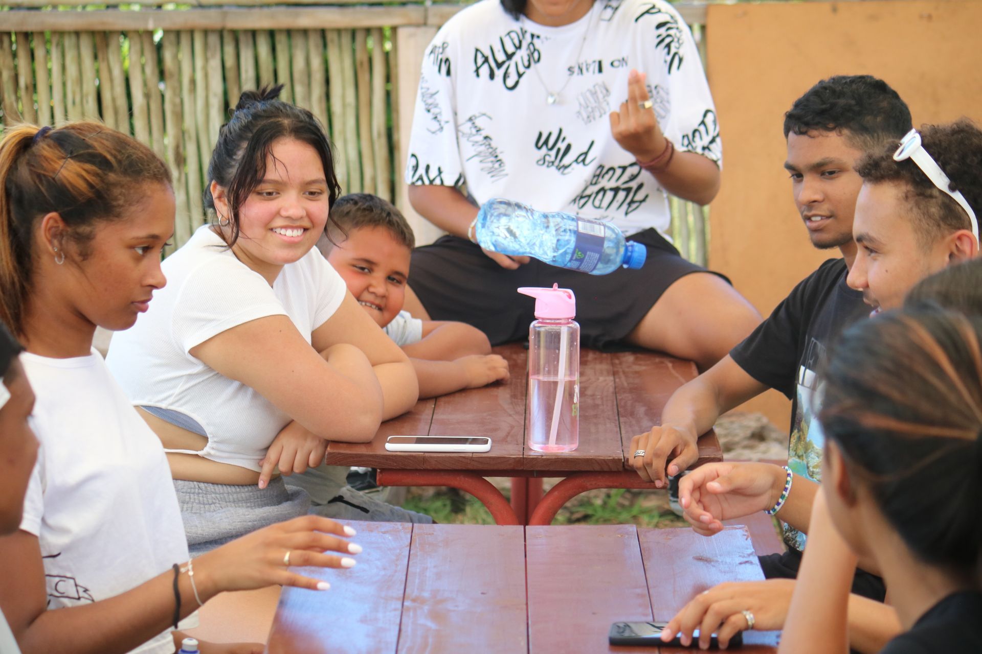 a group of people are sitting around a wooden table .