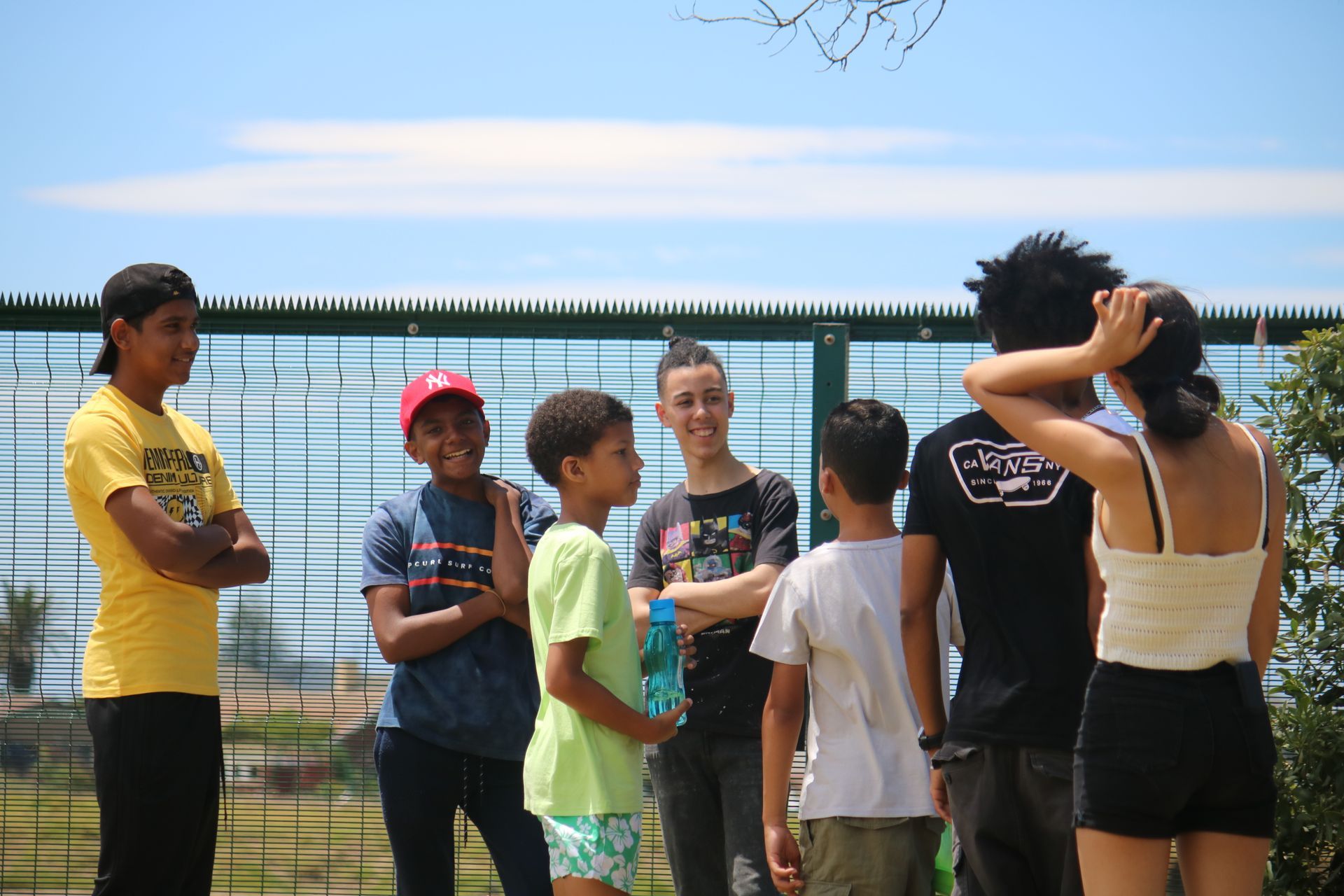 a group of young people are standing next to each other in front of a fence .
