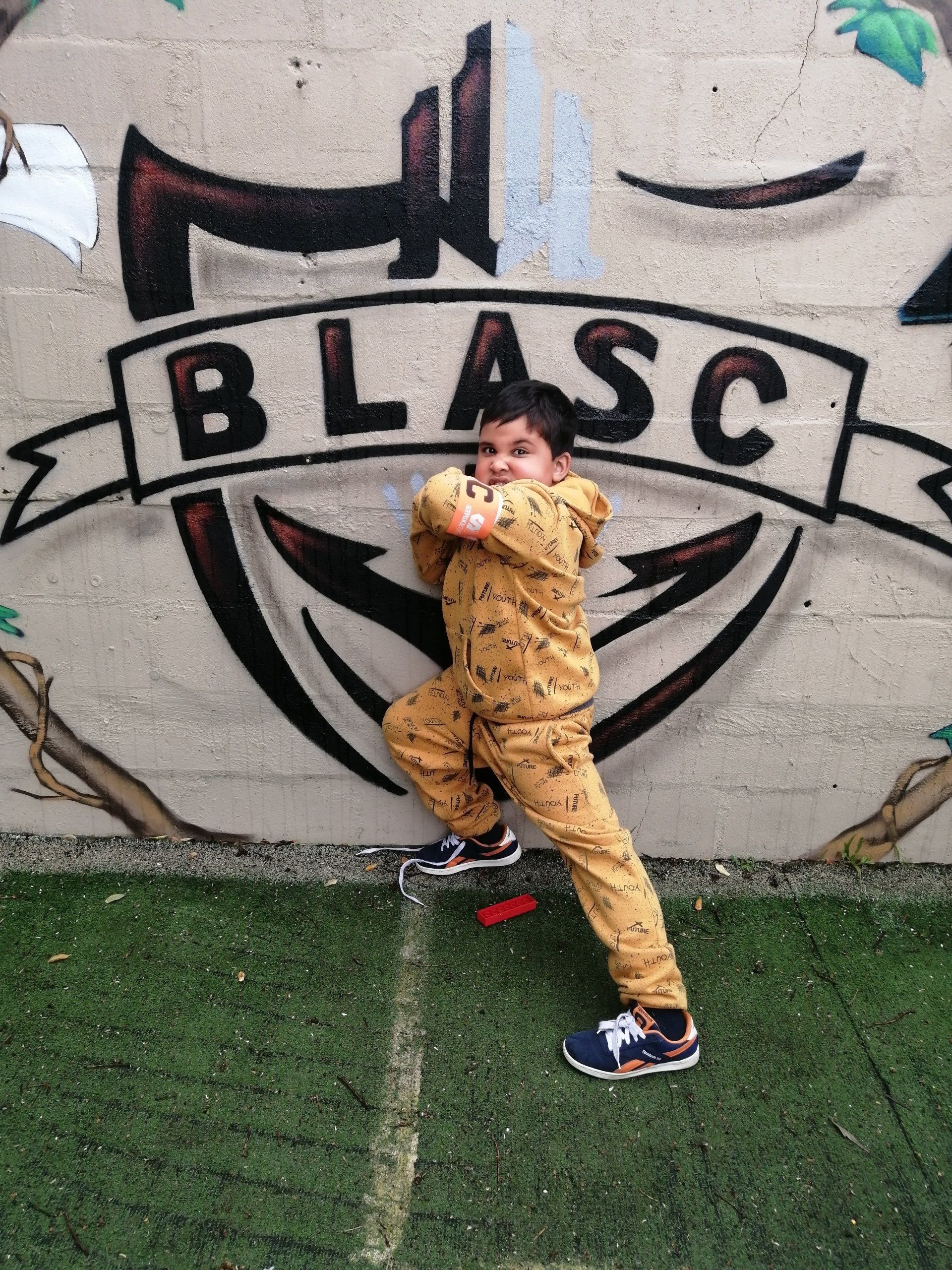 a young boy is standing in front of a wall that says blasc