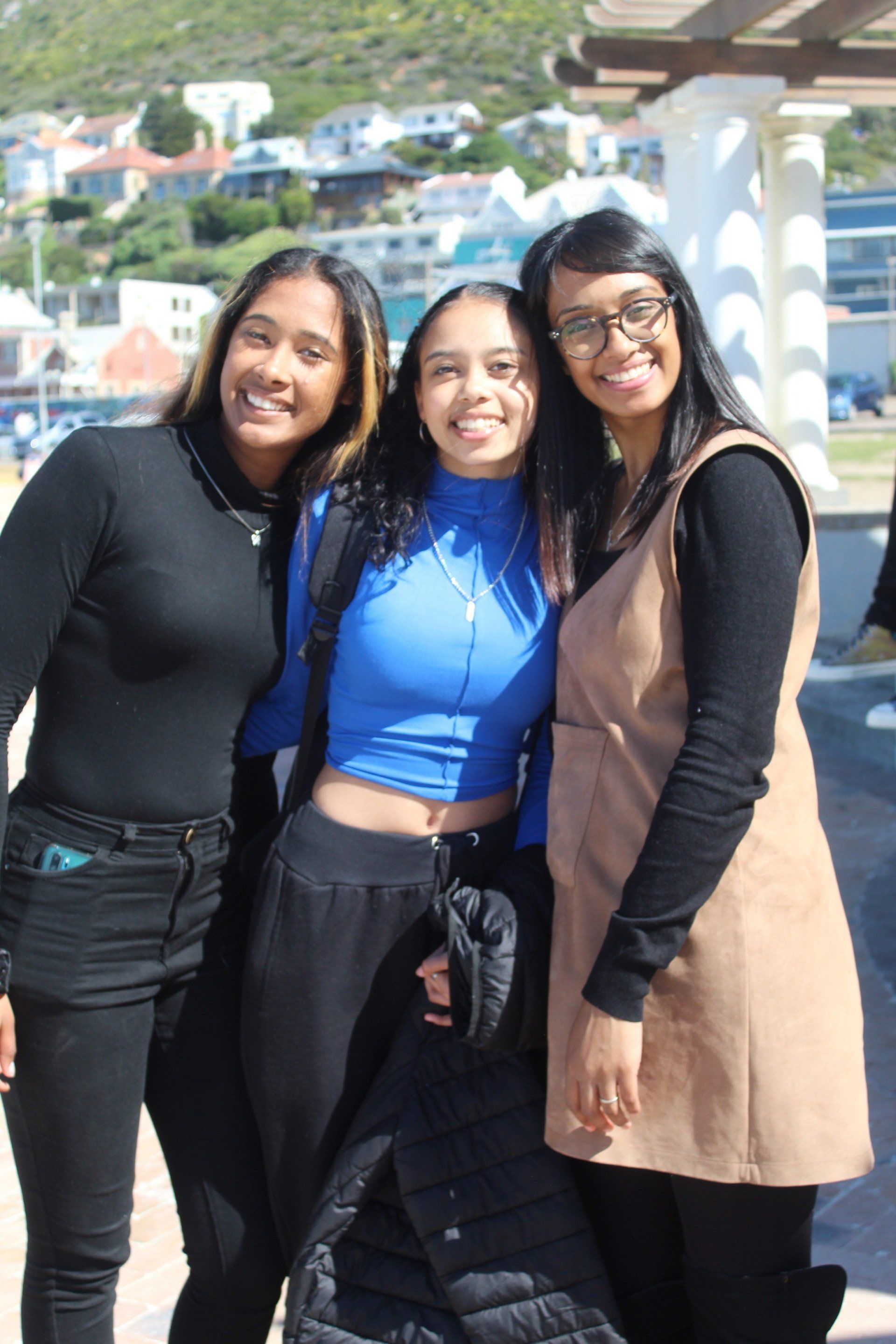 three young women are posing for a picture together and smiling .