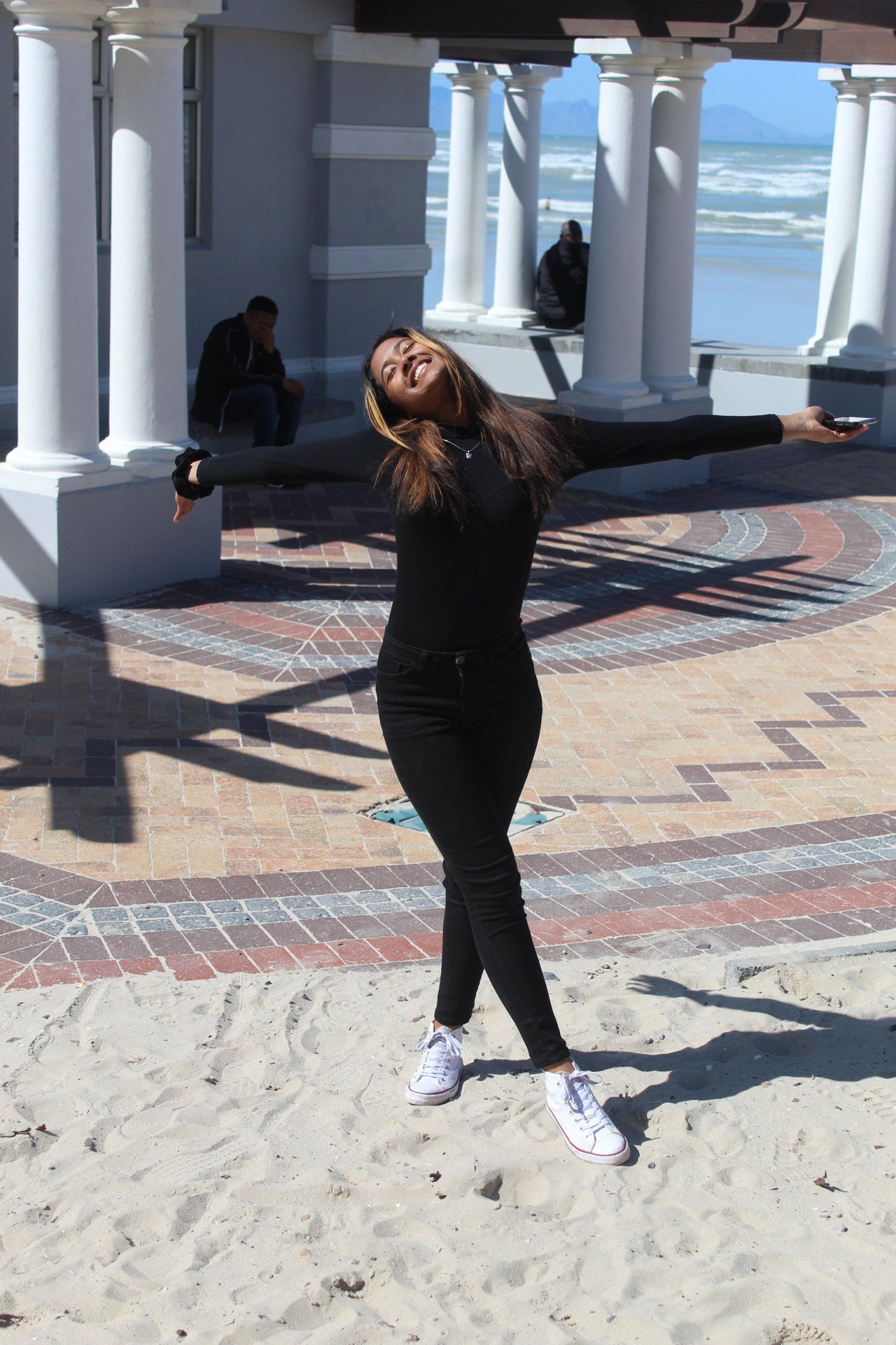 a woman is standing in the sand with her arms outstretched .