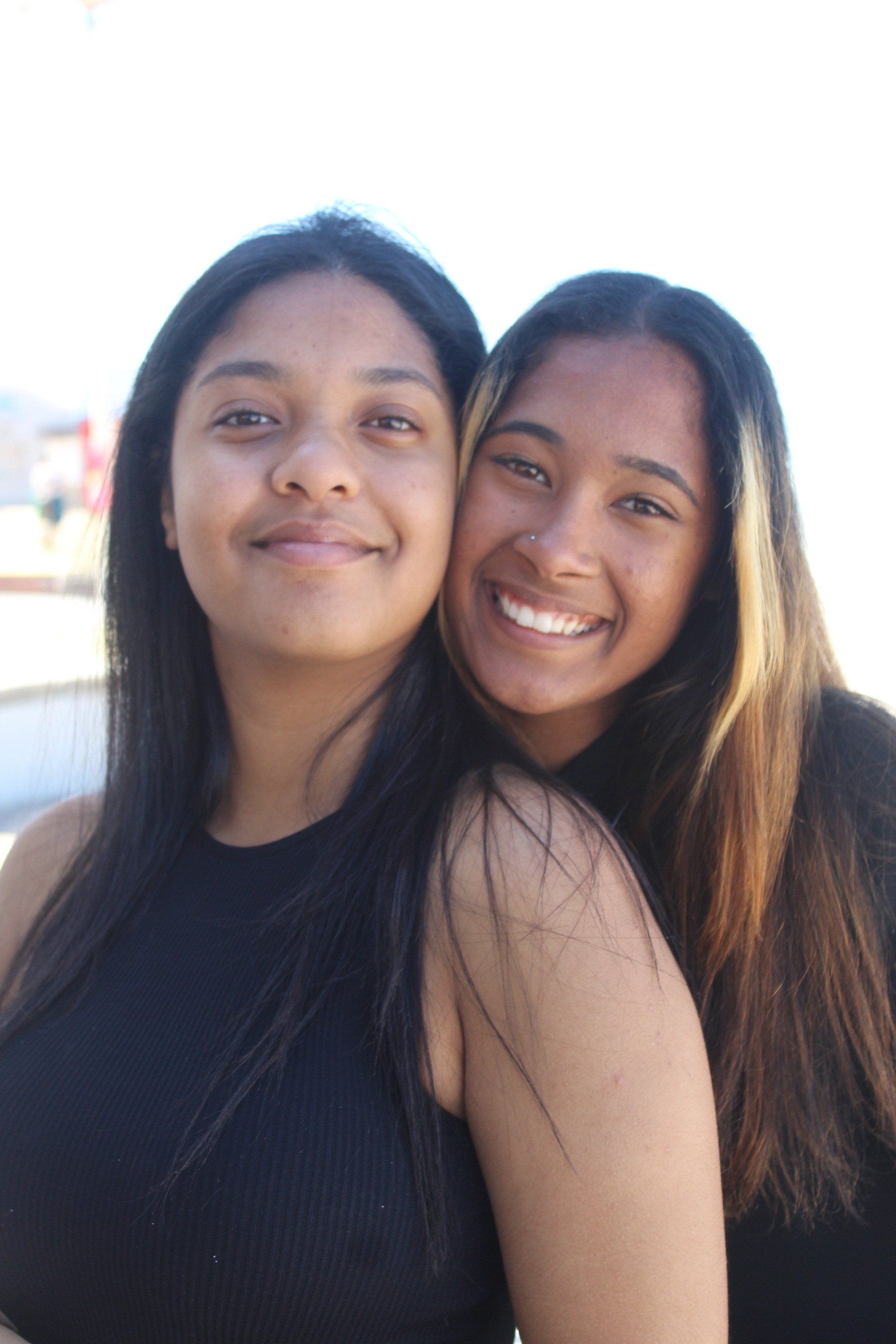 two young women are posing for a picture together and smiling .